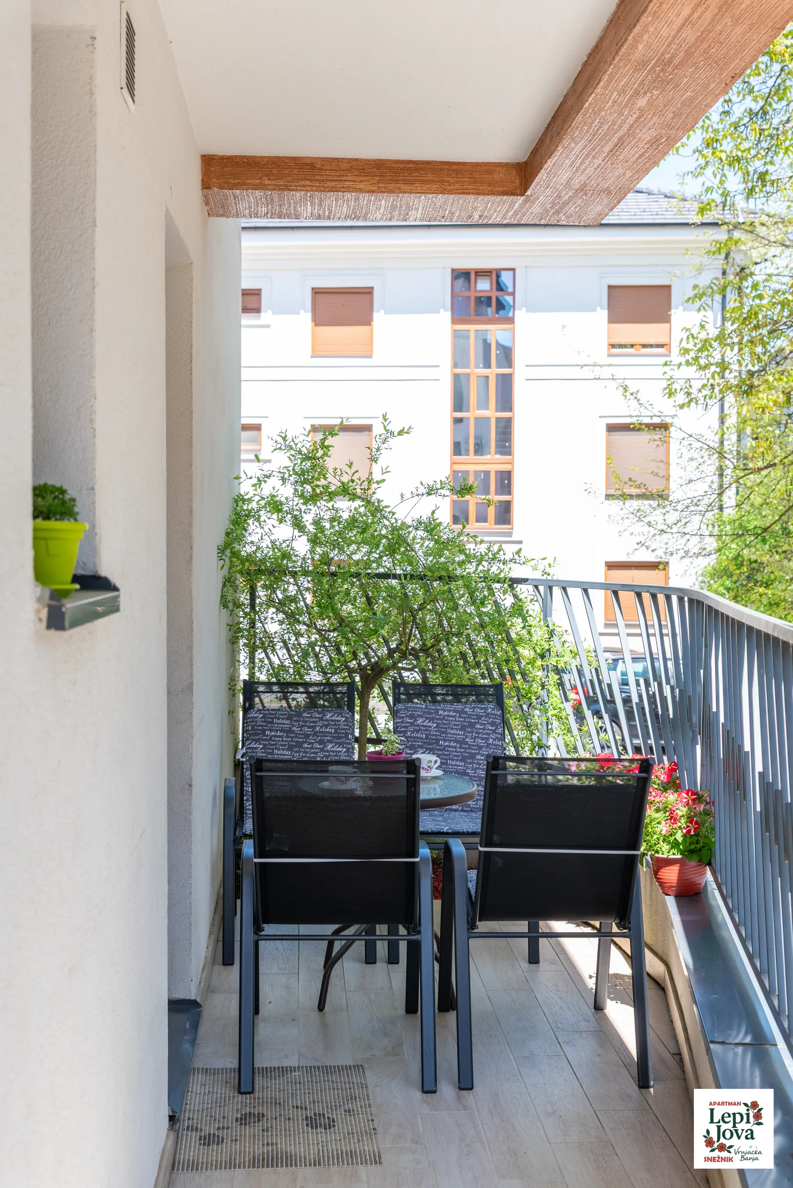 Sto i stolice na terasi apartmana Snežnik okruženi zelenilom